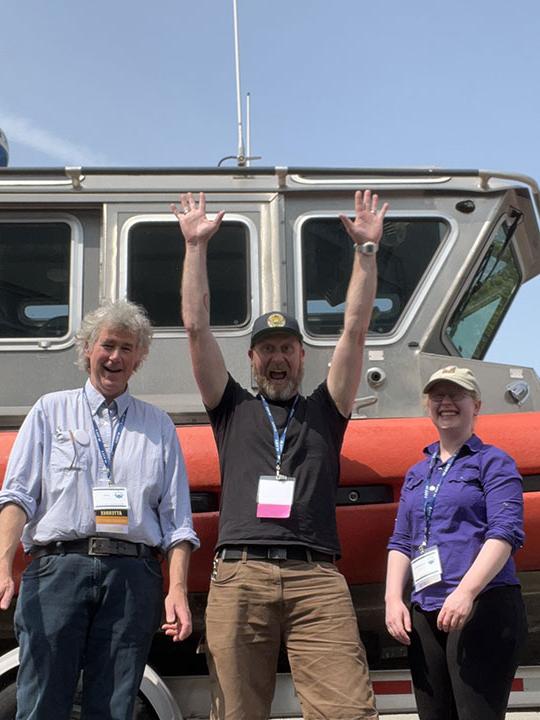 three people standing in front of a boat