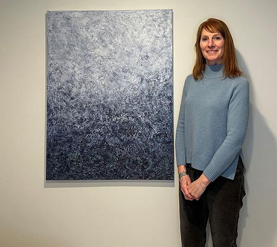 woman standing next to a painting