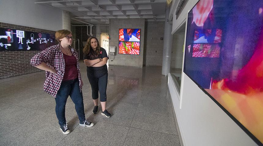 two students viewing art on digital screens